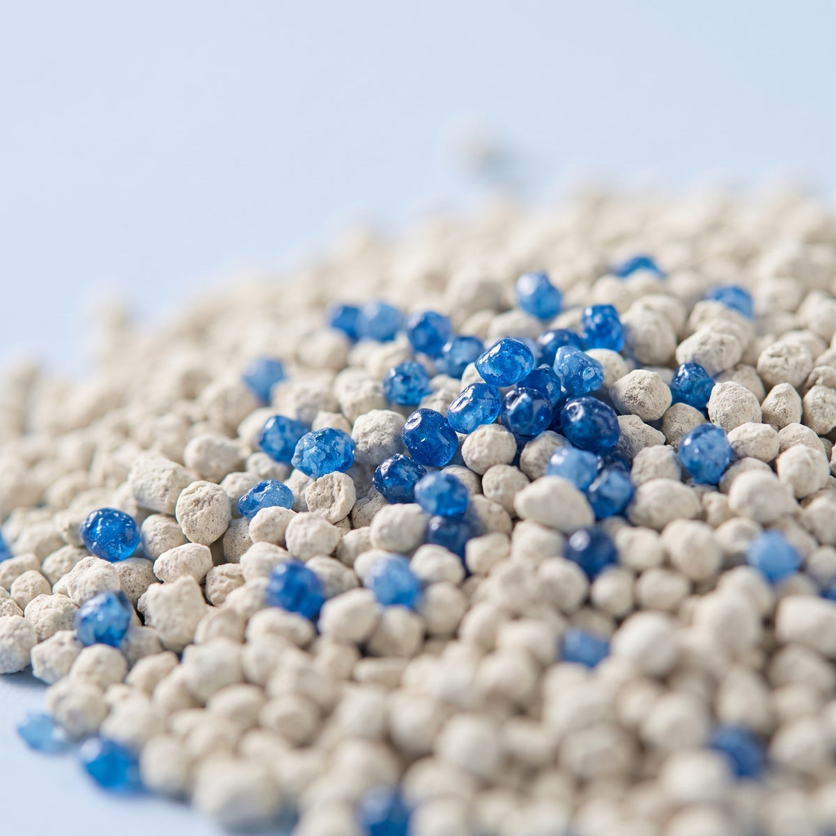 Litterly beads resting on cat litter, close up